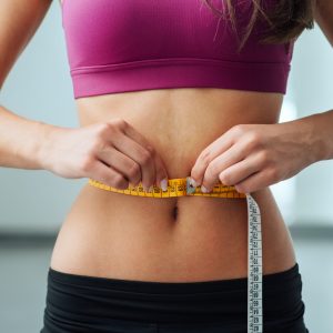 Slim Young Woman Measuring Her Thin Waist With A Tape
